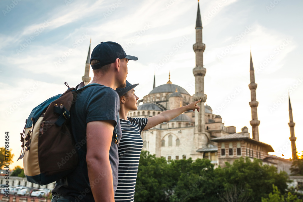 A pair of travelers near the world-famous Blue Mosque in Istanbul, Turkey. The girl shows direction.