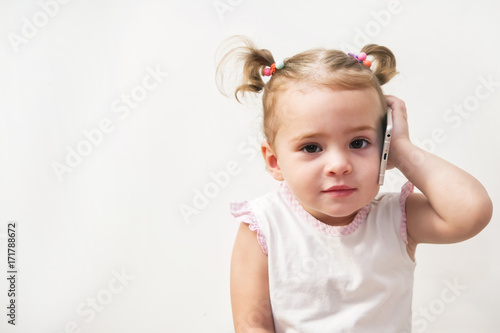 Baby girl speaking by cell phone, white background