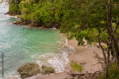 a high view looking down on a secluded beach cove with tropical forest nearby 