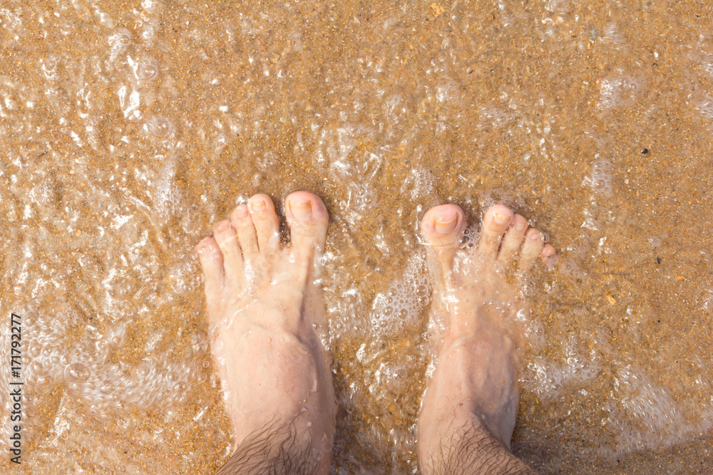 Foot on the sand. Transparent, clean water passes over your feet.