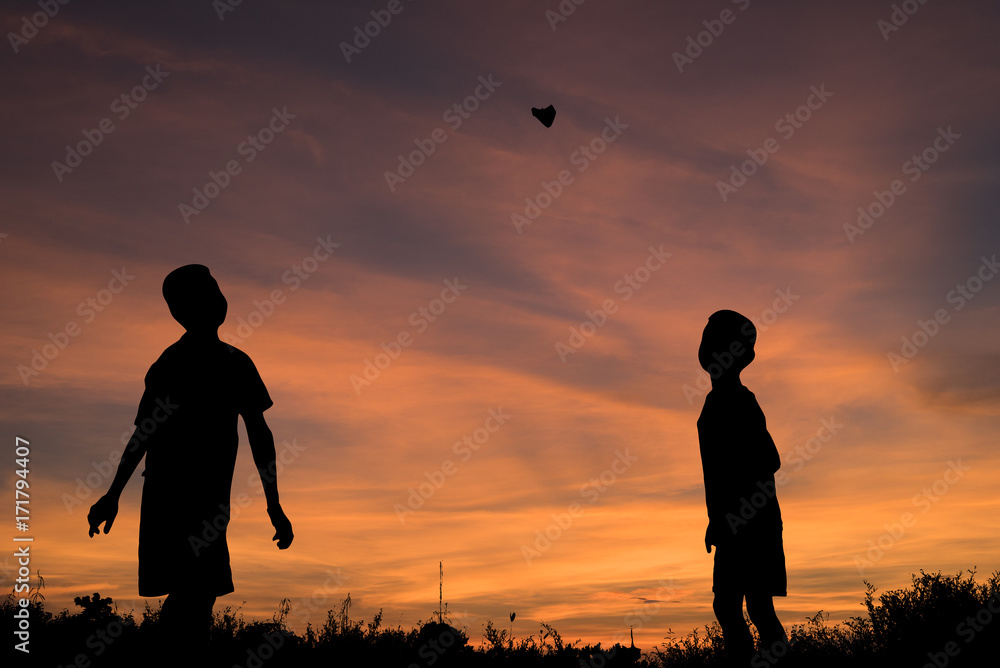 Silhouette of children a paper plane at sunset evoke childhood memories.