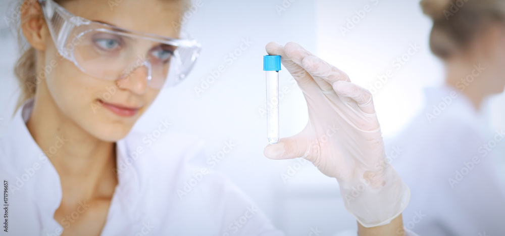 Female scientific researcher in laboratory studying substances or blood sample. Medicine and science concept