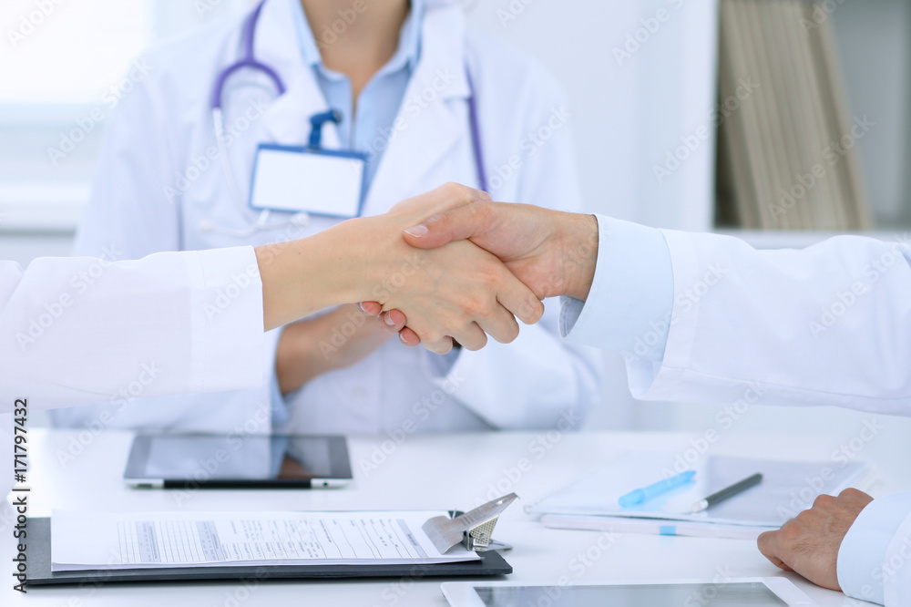 Doctors shaking hands to each other finishing up medical meeting Doctors shaking hands to each other finishing up medical meeting