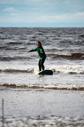 Photography Young little girl on beach taking surfing lessons