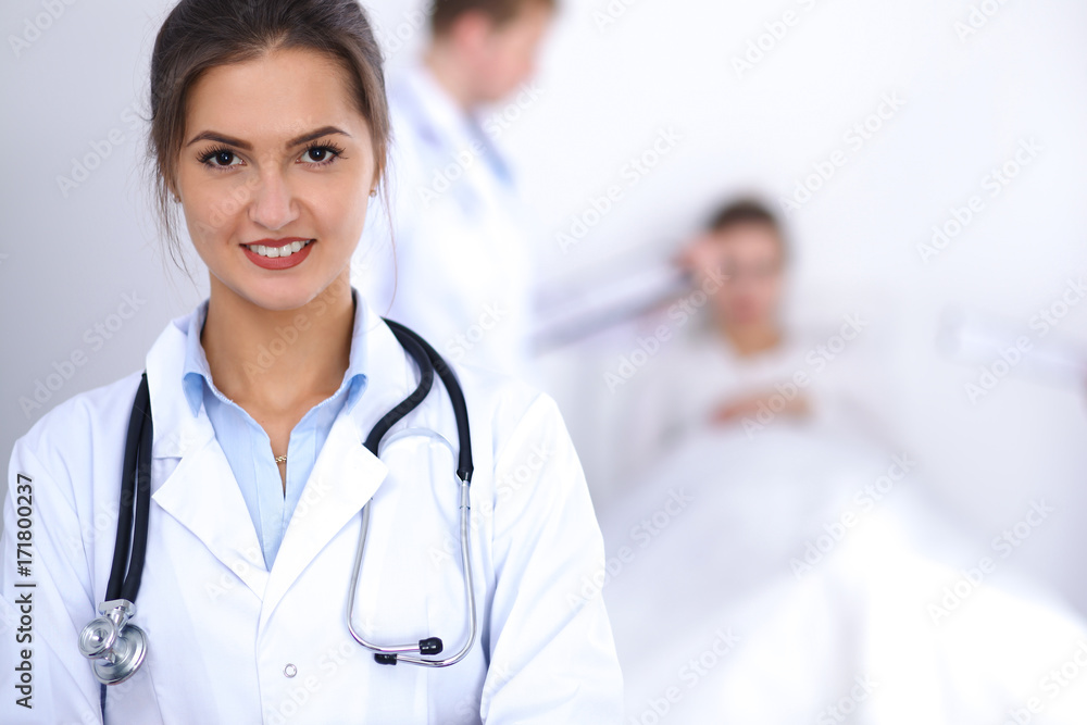 Female doctor smiling on the background with patient in the bed Female doctor smiling on the background with patient in the bed