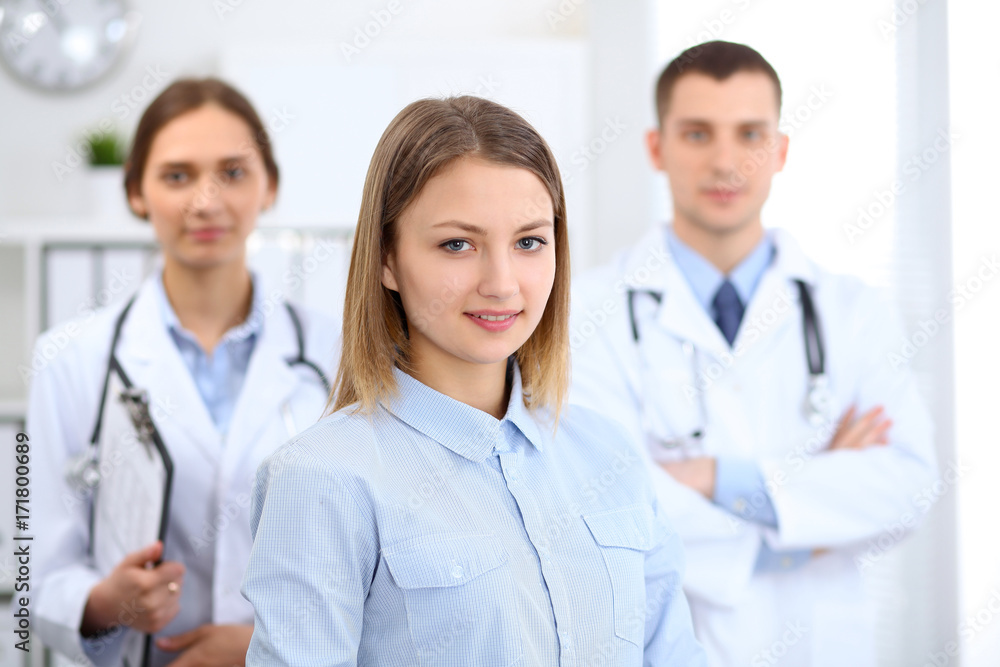 Happy smiling female patient with two cheerful doctors in the background. Medical and health care concept Happy smiling female patient with two cheerful doctors in the background. Medical and health care concept
