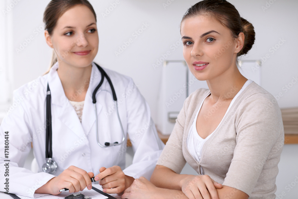 Doctor and patient sitting at the desk. The physician or therapist makes a diagnosis. Health care, medicine and patient service concept Doctor and patient sitting at the desk. The physician or therapist makes a diagnosis. Health care, medicine and patient service concept