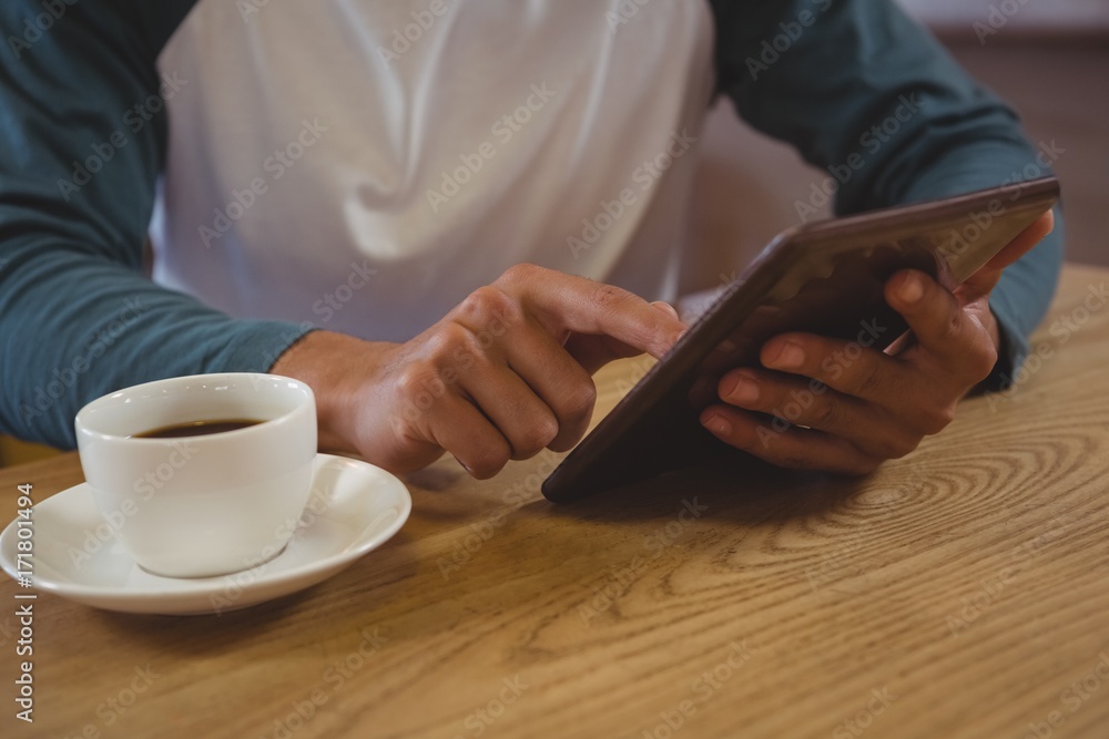 Fototapeta premium Mid section of man with coffee using tablet in cafe