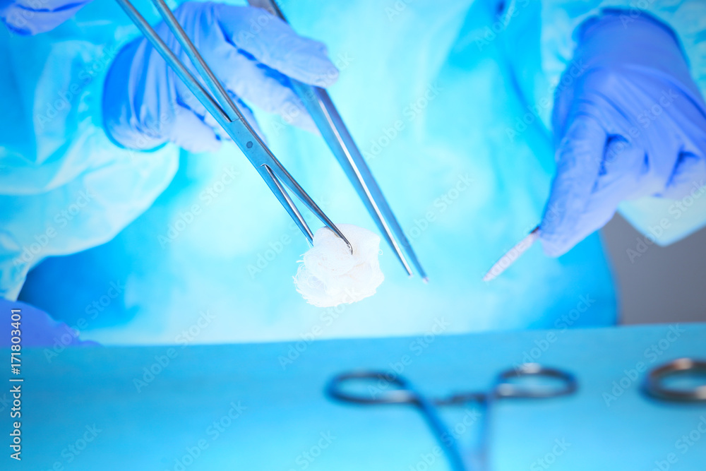 Close-up of of surgeons hands at work in operating theater toned in blue Close-up of of surgeons hands at work in operating theater toned in blue