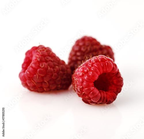 Close-up of three raspberry berries on white background.