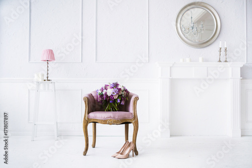 Bright white interior with lots of pink and pirple flowers on chair on wooden floor photo