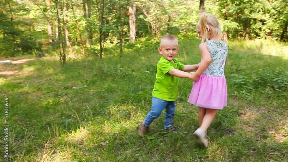 Funny kids - little girl and boy dancing and fall down on the grass Funny kids - little girl and boy dancing and fall down on the grass