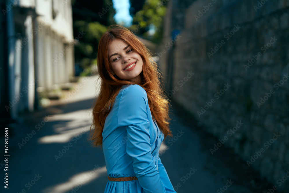1477989 Young beautiful woman in a blue dress in the city in the alley, smile