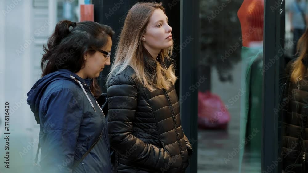 Two girls look a shop windows on a shopping mile Two girls look a shop windows on a shopping mile