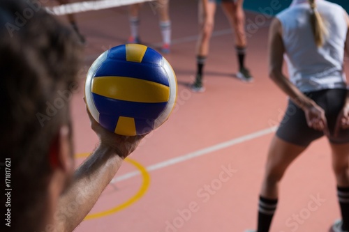 Cropped hand of player holding volleyball by female teammate