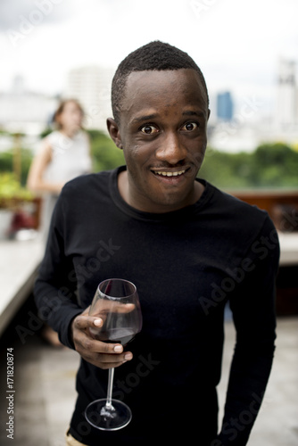 African ethnicity man holding a wine glass looking to camera
