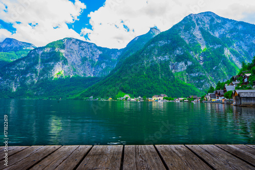 Popular beautiful village in Austria , Hallstatt in the green summer scenery and crystal clear water with the wooden plank as foreground  © vanila91