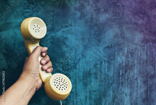Call from the Past Concept, Hand Raise a headphone over Grunge Concrete Cement wall, Vintage Retro color tone