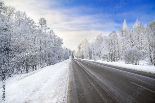winter landscape with asphalt road,forest and blue sky