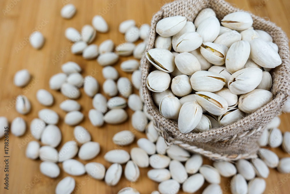 pistachios nuts in sack bag on wooden table pistachios nuts in sack bag on wooden table