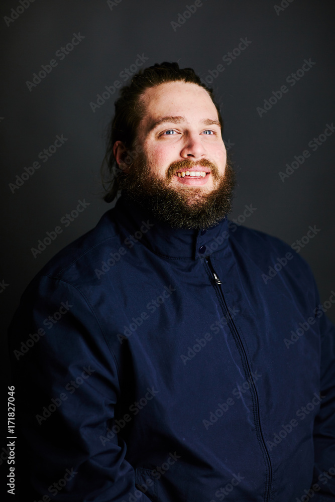 man with beard and long hair jacket zipped up ponytail staring at light