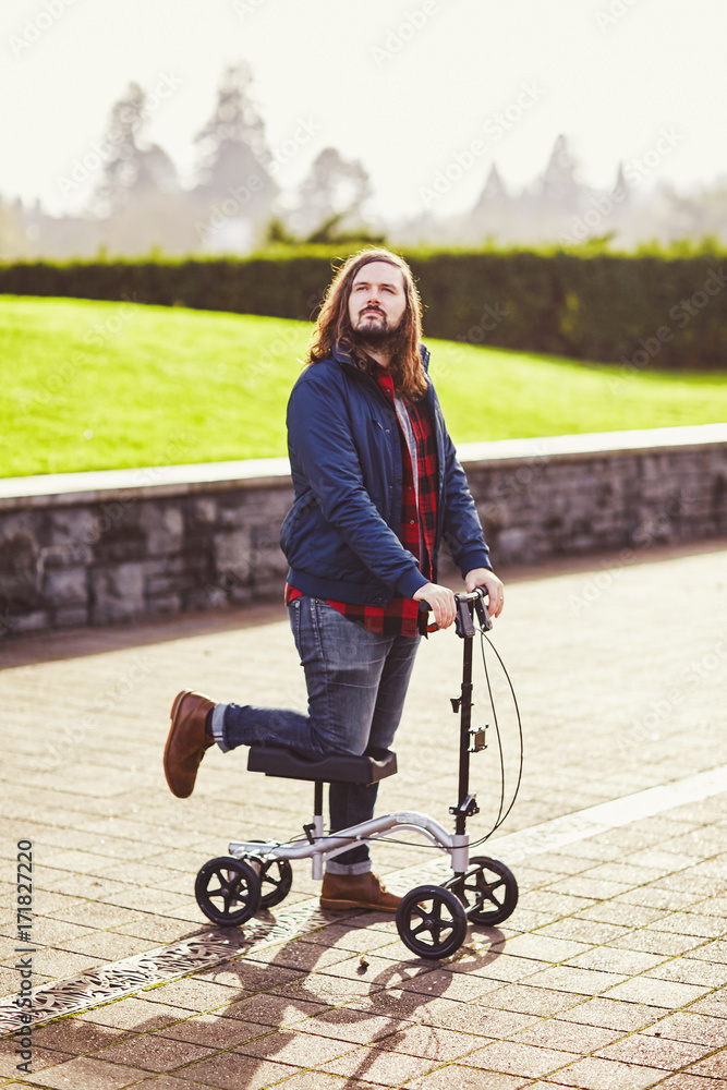 man with long hair on scooter for broken foot Stock Photo | Adobe Stock