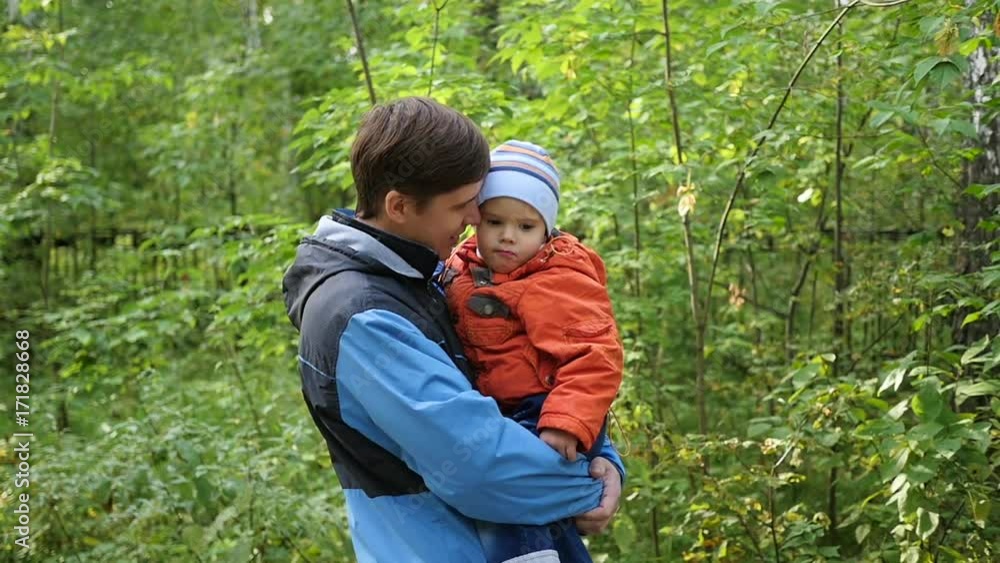 A young father holds his child in his arms. Tenderness and embrace of the beloved father. Outdoor activities A young father holds his child in his arms. Tenderness and embrace of the beloved father. Outdoor activities