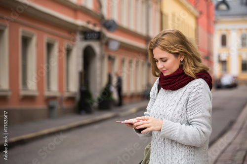 A woman looking at phone on a street in a European city