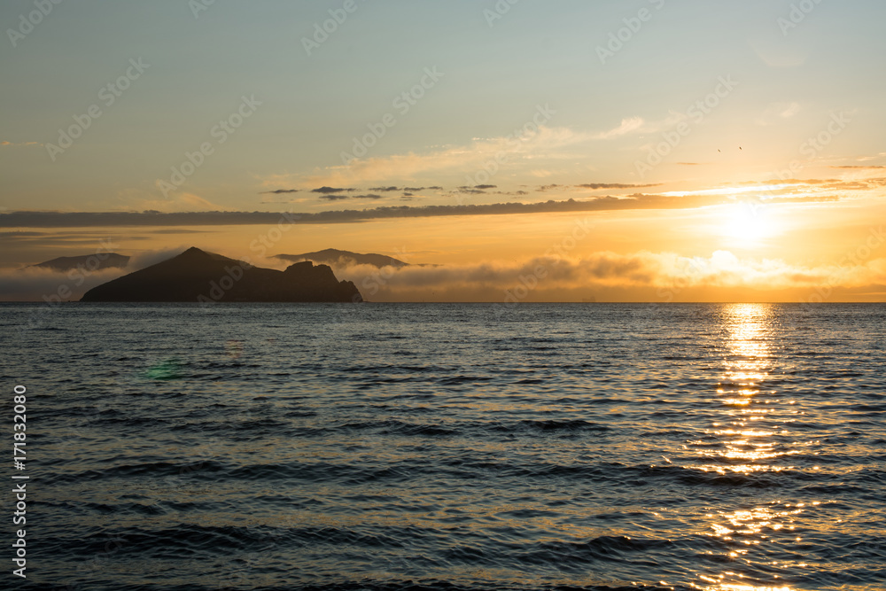 The sun rising above the water reflecting in the waves.