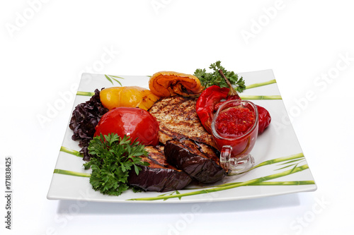 Prepared beef steak with vegetable decoration, close-up on a white background.