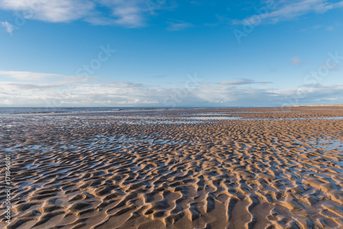 Beautiful blue sky and textured sand  on a cool sunny winters day at the beach