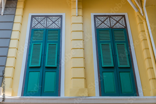 Ancient green window white frame on yellow wall exterior vintage style