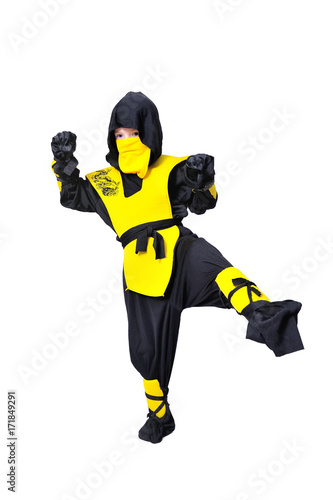 The seven-years old boy in black and yellow ninja suit with a hood and mask on his face bowed his head. With a knife in hand. Portrait in full growth
