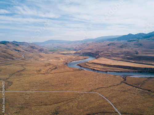 Aerial shot above blue river in grassland canyon