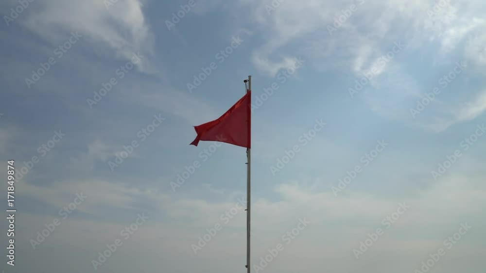 Red flag on the wind on the storm with sky at the background Red flag on the wind on the storm with sky at the background