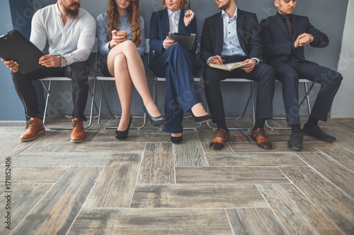 Tired of waiting. Bored businesspeople holding paper and looking away photo