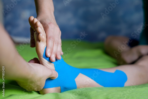 Doctor taping woman injury leg. photo