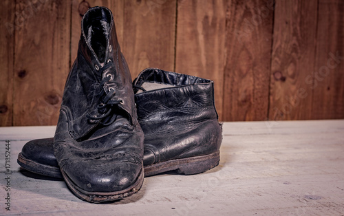 Old leather boots on dirt wooden background 