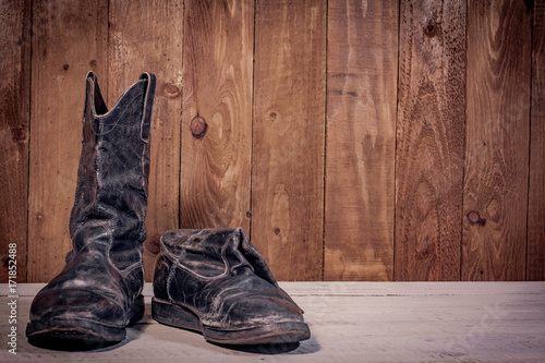 Old leather boots on dirt wooden background 