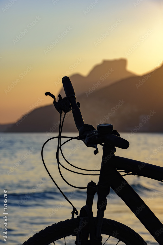 Naklejka premium Silhouette of bicycle in front of the beach during sunset