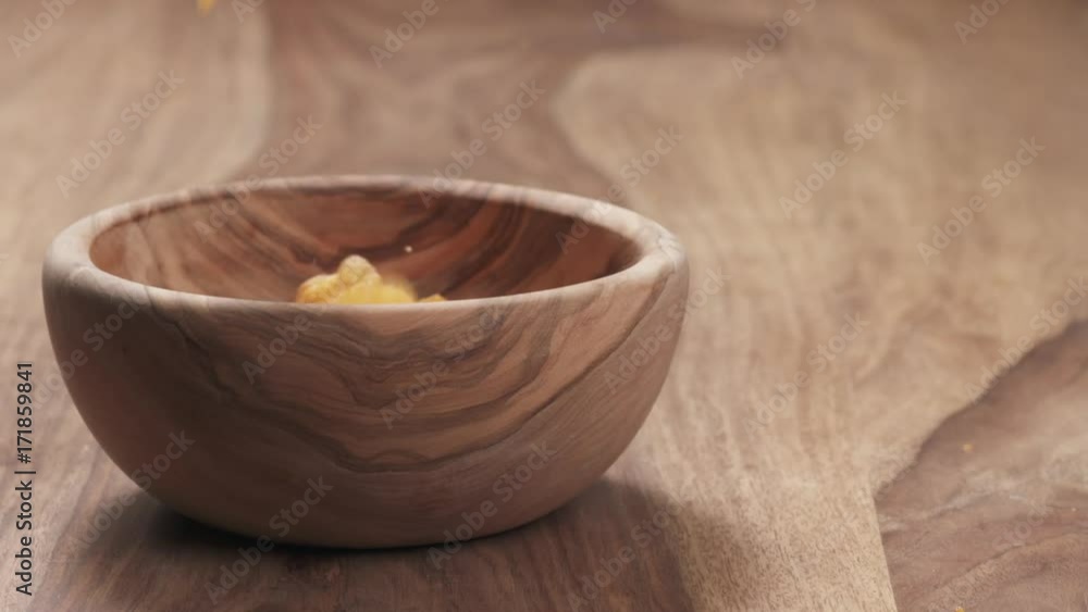 Slow motion potato chips with paprika falling in wooden bowl on wood table Slow motion potato chips with paprika falling in wooden bowl on wood table