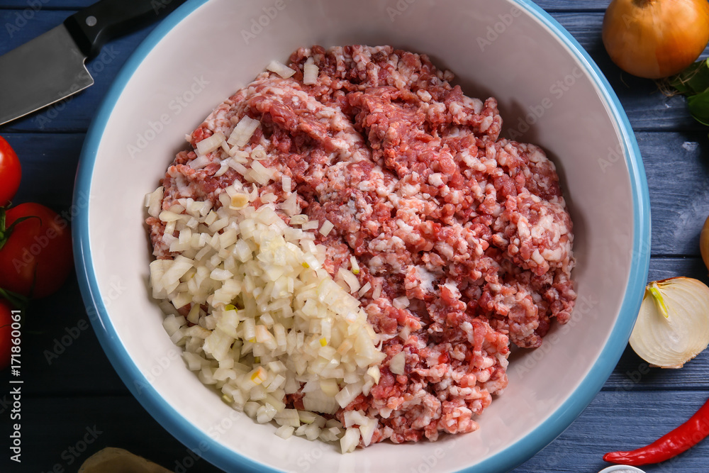 Bowl with ground turkey and ingredients for delicious meatloaf on wooden table Bowl with ground turkey and ingredients for delicious meatloaf on wooden table