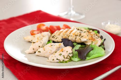 Plate with tasty chicken meat and tomatoes on table. Cooking for one concept