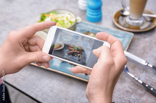 Man photographing tasty food with mobile phone, closeup