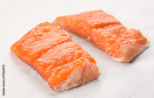 Two slices of red fish fillet on white paper, closeup