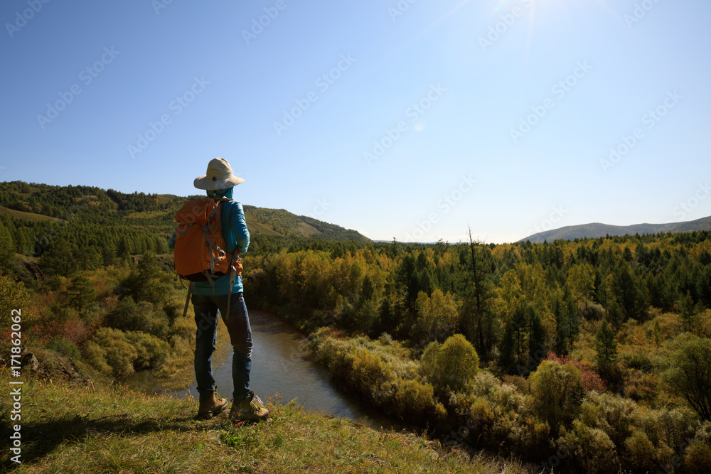 woman hiking with backpack at the riverside mountain