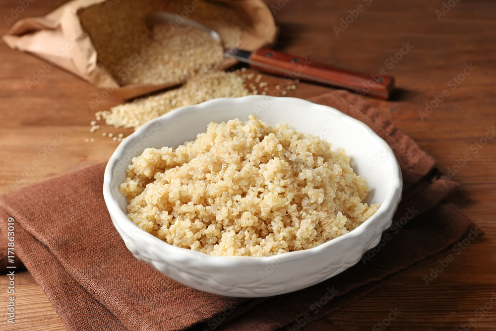 Bowl with boiled white quinoa grains on wooden table Bowl with boiled white quinoa grains on wooden table
