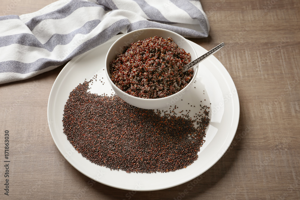 Dishware with boiled and raw quinoa grains on wooden table Dishware with boiled and raw quinoa grains on wooden table