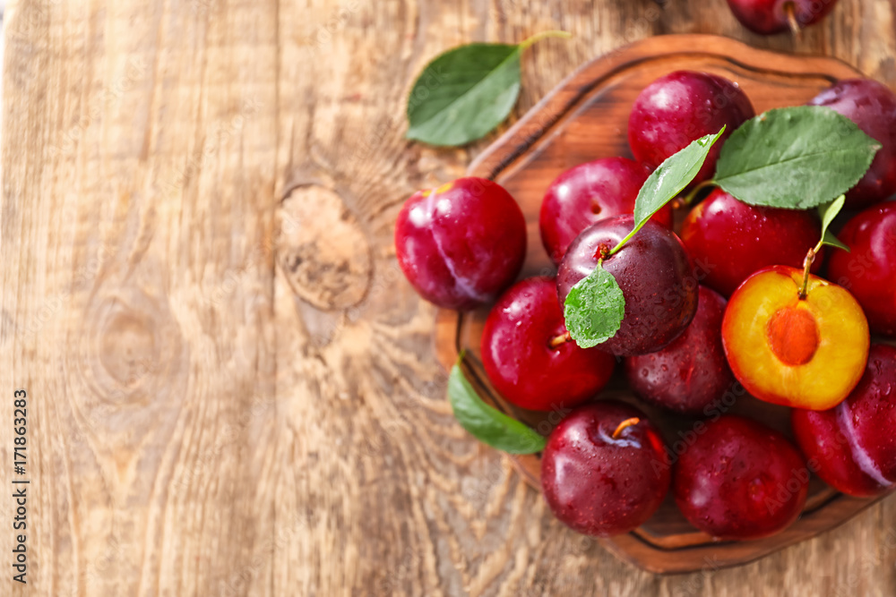 Board with fresh ripe plums on wooden table Board with fresh ripe plums on wooden table