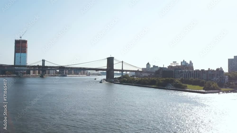 Aerial view of Brooklyn bridge through East river in New York, America. Drone flying over water in Brooklyn district Aerial view of Brooklyn bridge through East river in New York, America. Drone flying over water in Brooklyn district